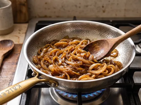 A batch of onions caramelizing in a Kaizen titanium pan